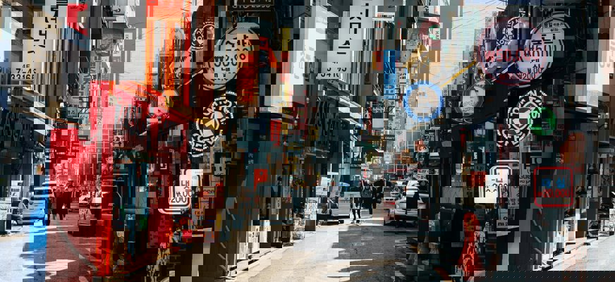 En solig gatubild från Seoul, Sydkorea, med färgglada skyltar och människor som promenerar.