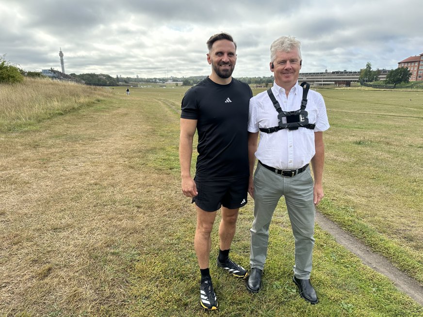 Niklas Mattsson med ledsagningstekniken i hölster på bröstet tillsammans med Fatmir Seremeti, i bakgrunden syns Kaknästornet.