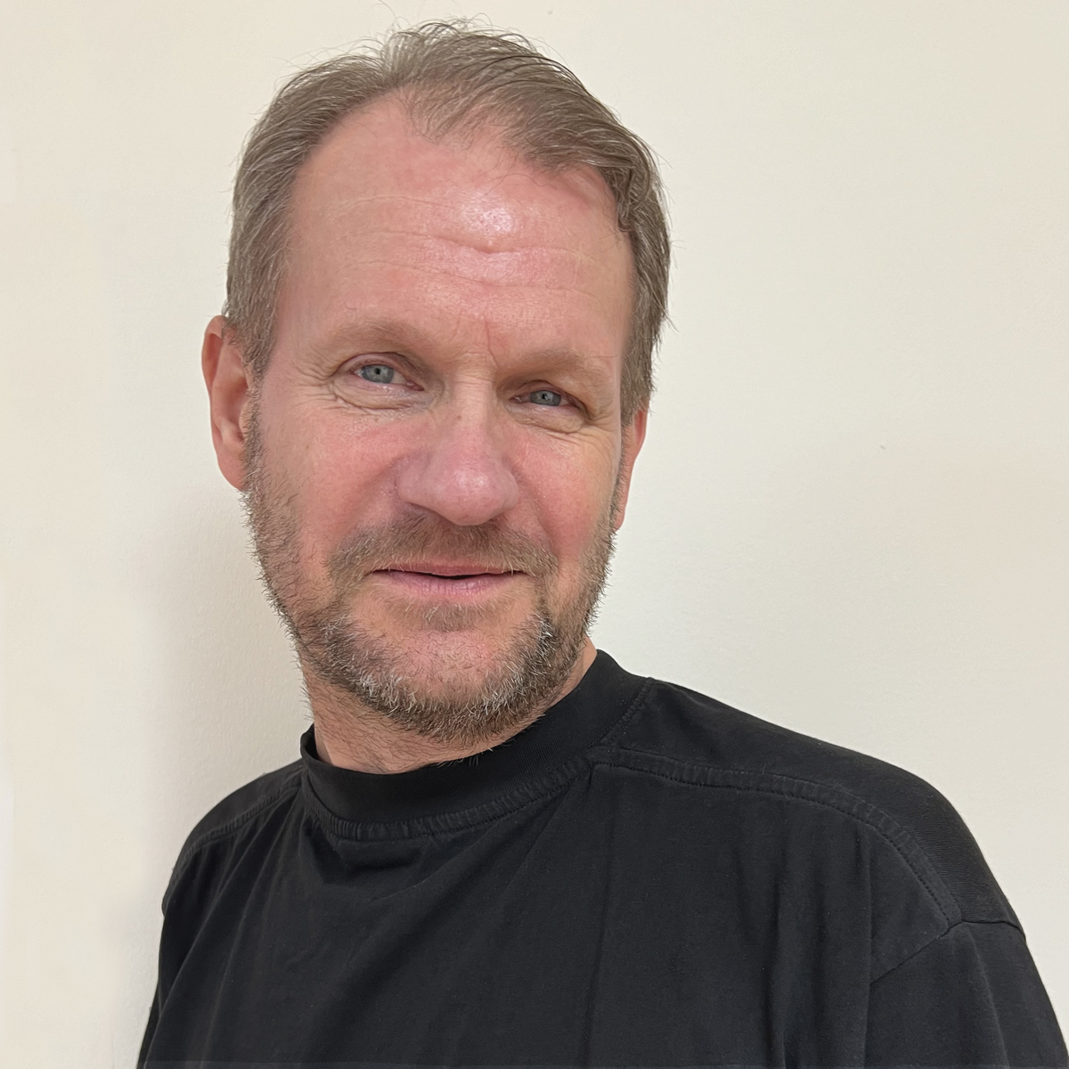 Man i 50-årsåldern, kort brunrött hår, kort skägg, svart t-shirt.