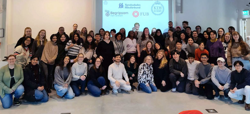 Ett gruppfoto taget på slutet av ett diskussionsforum om tillgänglighet på KTH. Bilden visar cirka 50 studenter, både från Sverige men även från andra delar av världen, tillsammans med ansvarig lärare Sofia Strömqvist och rekryterade experter. Deltagarna står samlade i ett klassrum framför en projicerad display. På displayen i bakgrunden syns logotyper för KTH samt organisationerna Synskadades Riksförbund (SRF), FUB och Begripsam.