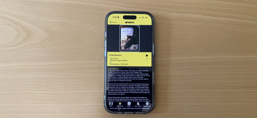 En mobiltelefon som visar information om filmen Draktränaren i syntolkningsappen Greta.