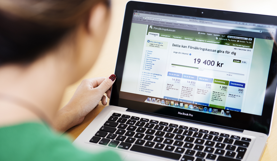 Kvinna fotad bakifrån. Sitter vid laptop, surfar på Försäkringskassans webb och tjänsten "Kassakollen".