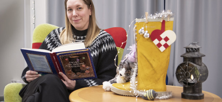 Monica Korp sitter i en fåtölj med en bok i händerna.