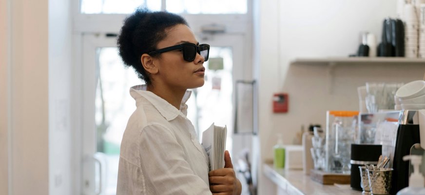 En kvinna (inte Marie i texten) med mörkt hår och mörka solglasögon står i ett kök. Hon syns i profil, bär en vit skjorta och handen vilar på bänkskivan framför henne.