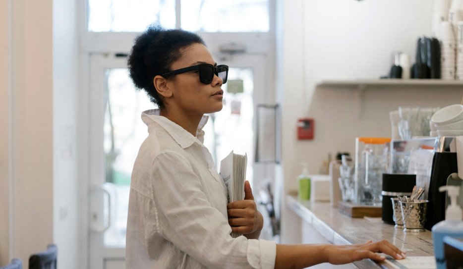 En kvinna (inte Marie i texten) med mörkt hår och mörka solglasögon står i ett kök. Hon syns i profil, bär en vit skjorta och handen vilar på bänkskivan framför henne.