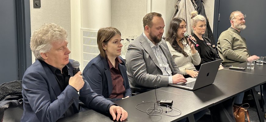 SRF:s Niklas Mattsson, Belmina Koca och Anders Ziethén tillsammans med representanter från US och FSDB. De sitter uppradade vid ett bord. Niklas Mattsson och Kadria Alizadeh från US pratar i mikrofoner.