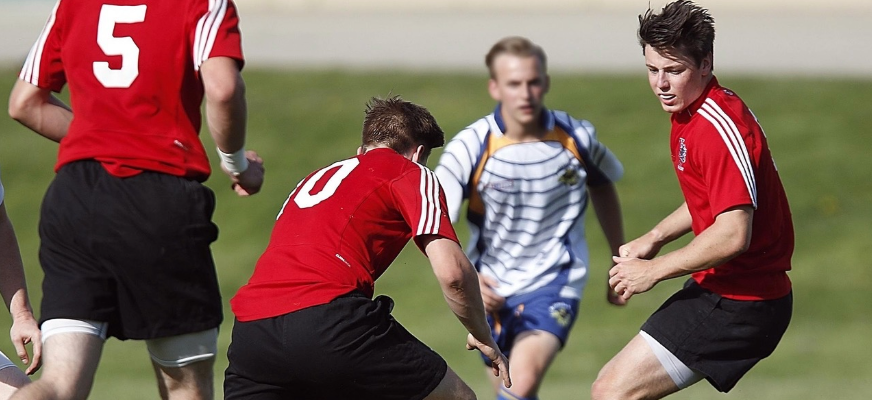 Fyra ungdomar springer efter en boll på en gräsmatta.