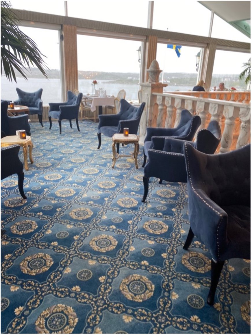 Lounge med fotöljer, bord, kristallkronor och stora panoramafönster med havsutsikt