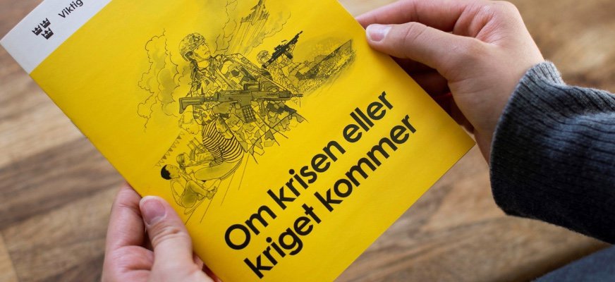 Ett par händer håller i broschyren ”Om krisen eller kriget kommer”.