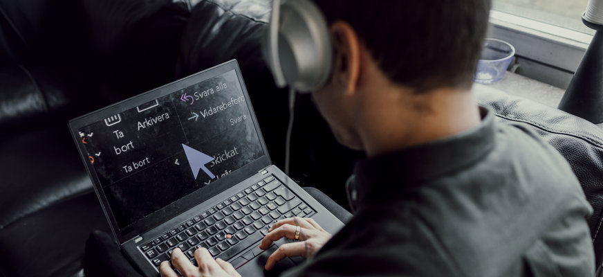 Person med hörlurar vid en laptop med förstoring