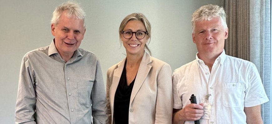 Linda Lindberg står mellan Niklas Mattsson, SRF:s ordförande, och Lennart Karlsson, sakkunnig på SRF i ett mötesrum på SD:s riksdagskansli.