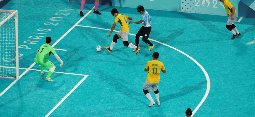 Tre spelare och en målvakt springer efter bollen på en 5-a-side-plan. Bilden är från Paralympics i Paris 2024.