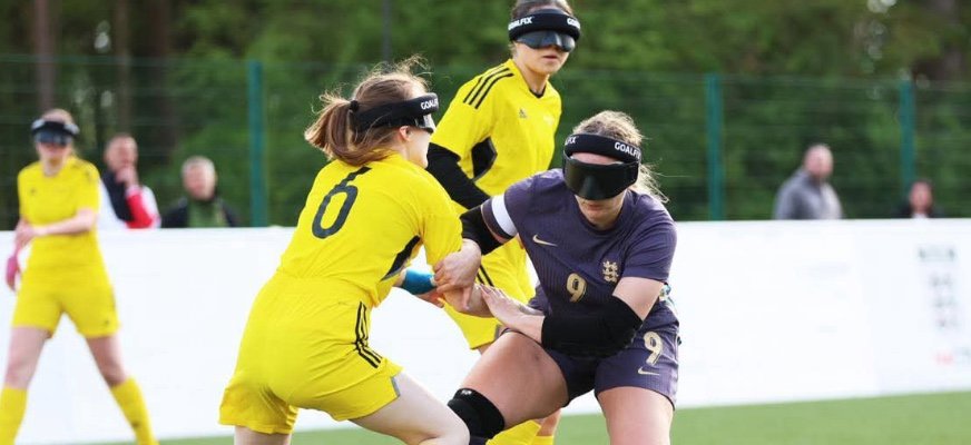 Sofia Boström och en motståndare i en närkamp på en fotbollsplan av gräs. Fotbollen ligger mellan dem på marken. Sofia är iklädd Sveriges gula landslagskläder med nummer 6 på ryggen. Hon har håret i en hästsvans.