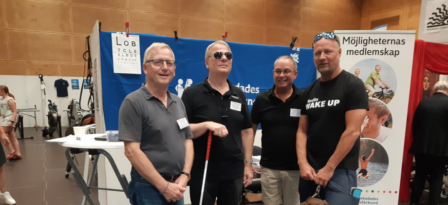 4 män med mörka tröjor framför utställningsmonter.