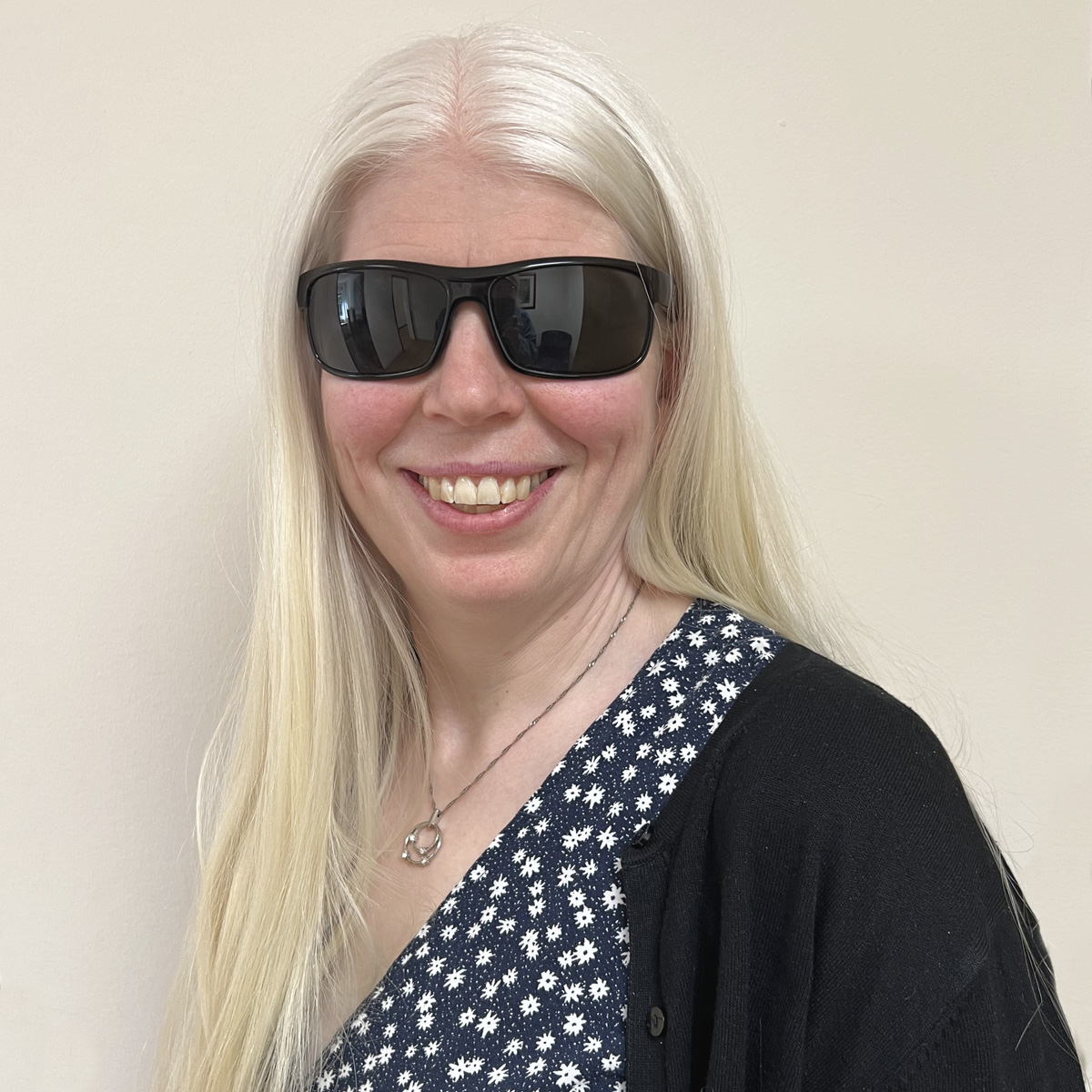 Leende kvinna i 45-årsåldern, mycket ljust långt hår, svarta solglasögon.