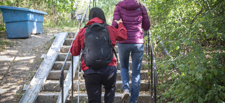 Person ledsagas uppför trappa