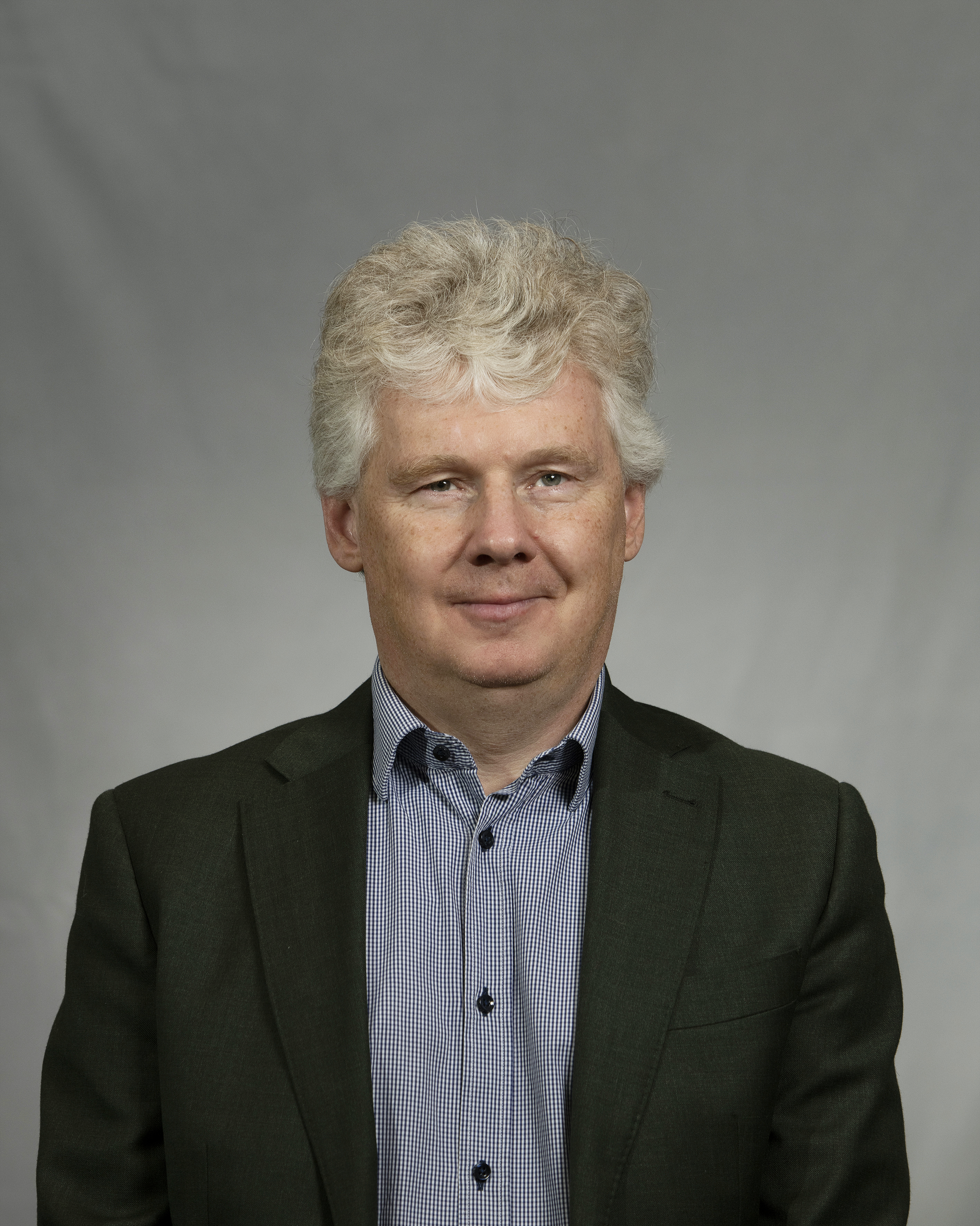 Porträttbild Niklas Mattsson, allvarligt uttryck i grått hår, skjorta och kavaj.