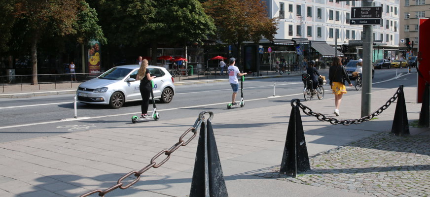 Personer åker elsparkcykel i stadsmiljö