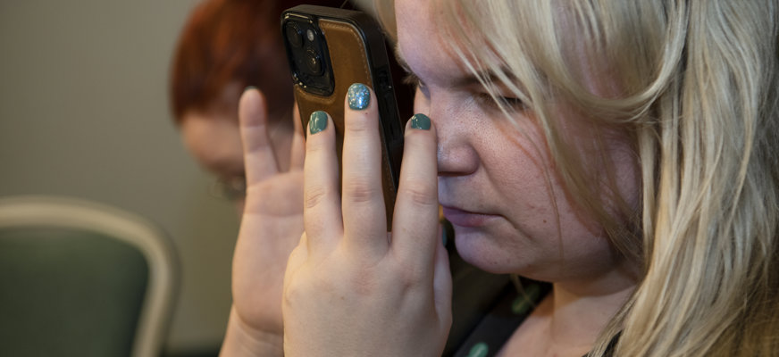 Blond kvinna tittar mycket nära på smartphone