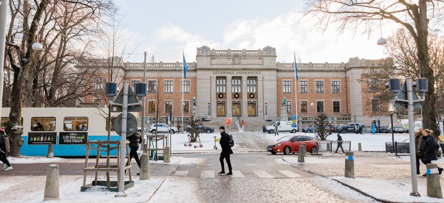 I förgrund syns spårvagnsspår, en spårvagn, en bil och gångtrafikanter. I bakgrund Göteborgs universitet.