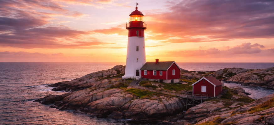 En vit fyr med röd topp på en kulle som lyses upp av en solnedgång som färgar