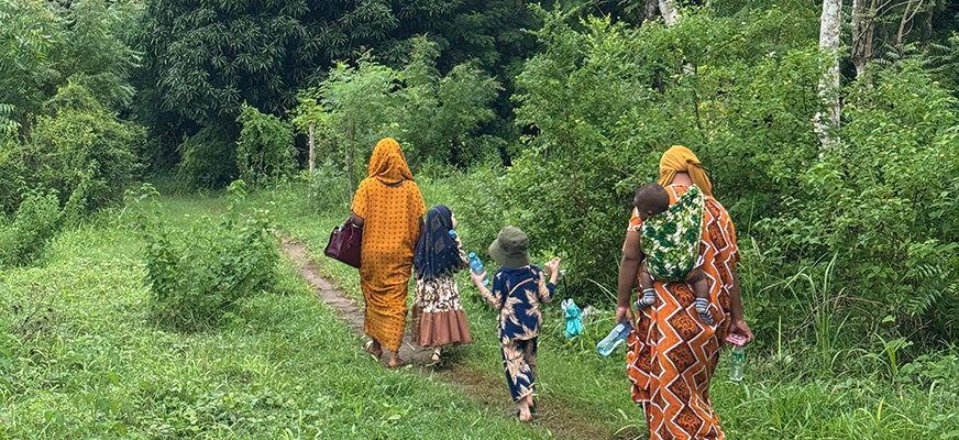 Två Tanzaniska kvinnor promenerar tillsammans på en skogsstig i Dar es Salaam. Med sig har de tre barn, varav två har albinism och vit hy.